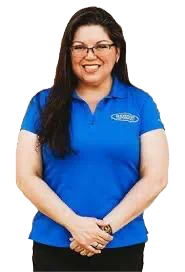 Woman in a blue polo shirt smiling and standing with hands clasped in front.