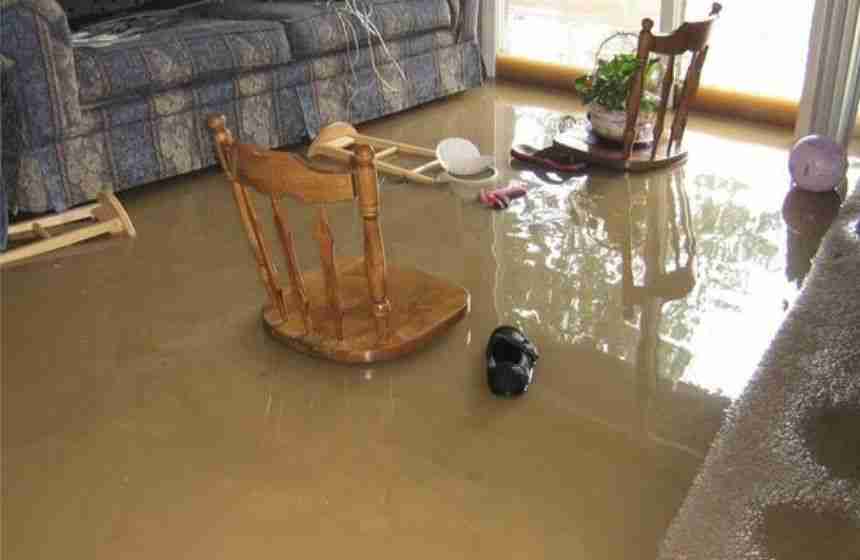 Living room flooded with dirty water and floating furniture, showing the dangers of black water.