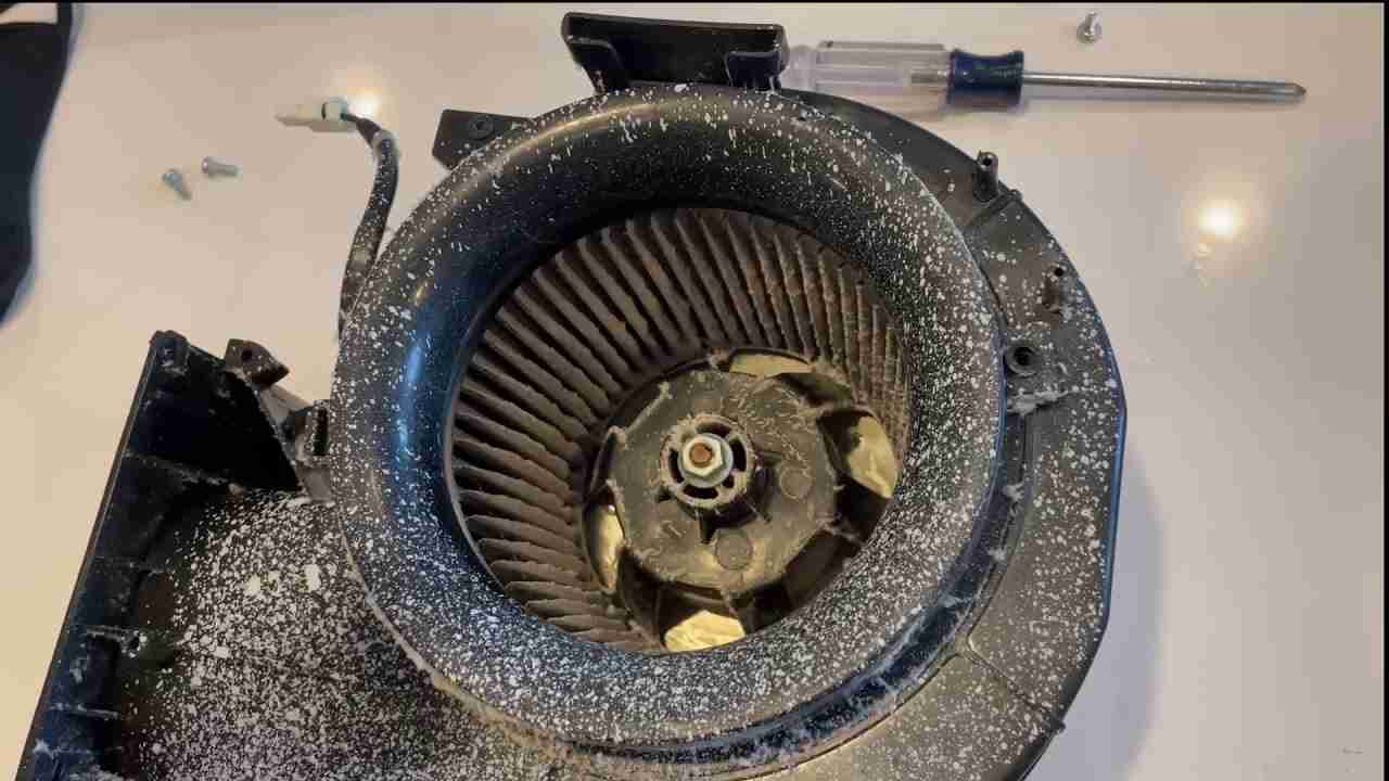 Dust-covered exhaust fan motor with visible debris buildup, indicating poor maintenance and airflow obstruction.