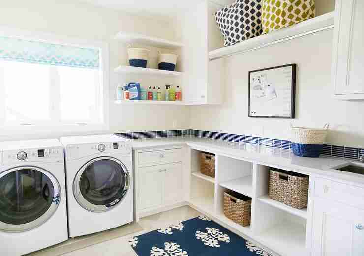 Bright and organized laundry room with front-load washer and dryer, open shelving, storage baskets, and a large window for natural light.