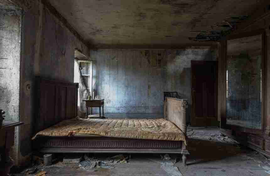 A heavily damaged bedroom with soot-covered walls and smoke stains from a house fire. This image illustrates the lingering effects of smoke damage long after the flames are gone.