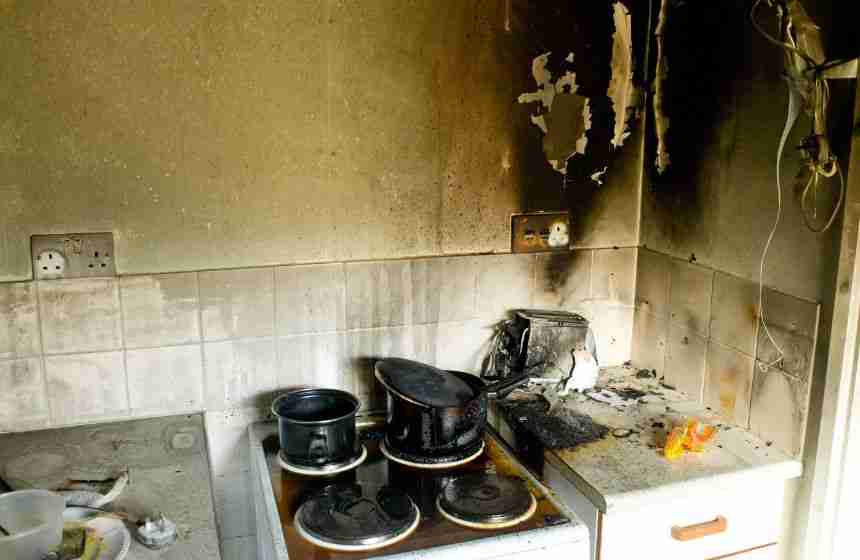 A kitchen in Houston, TX shows severe fire damage with charred appliances, soot-covered walls, and melted wiring. This scene highlights the destructive impact of fire and the urgent need for professional fire damage repair.