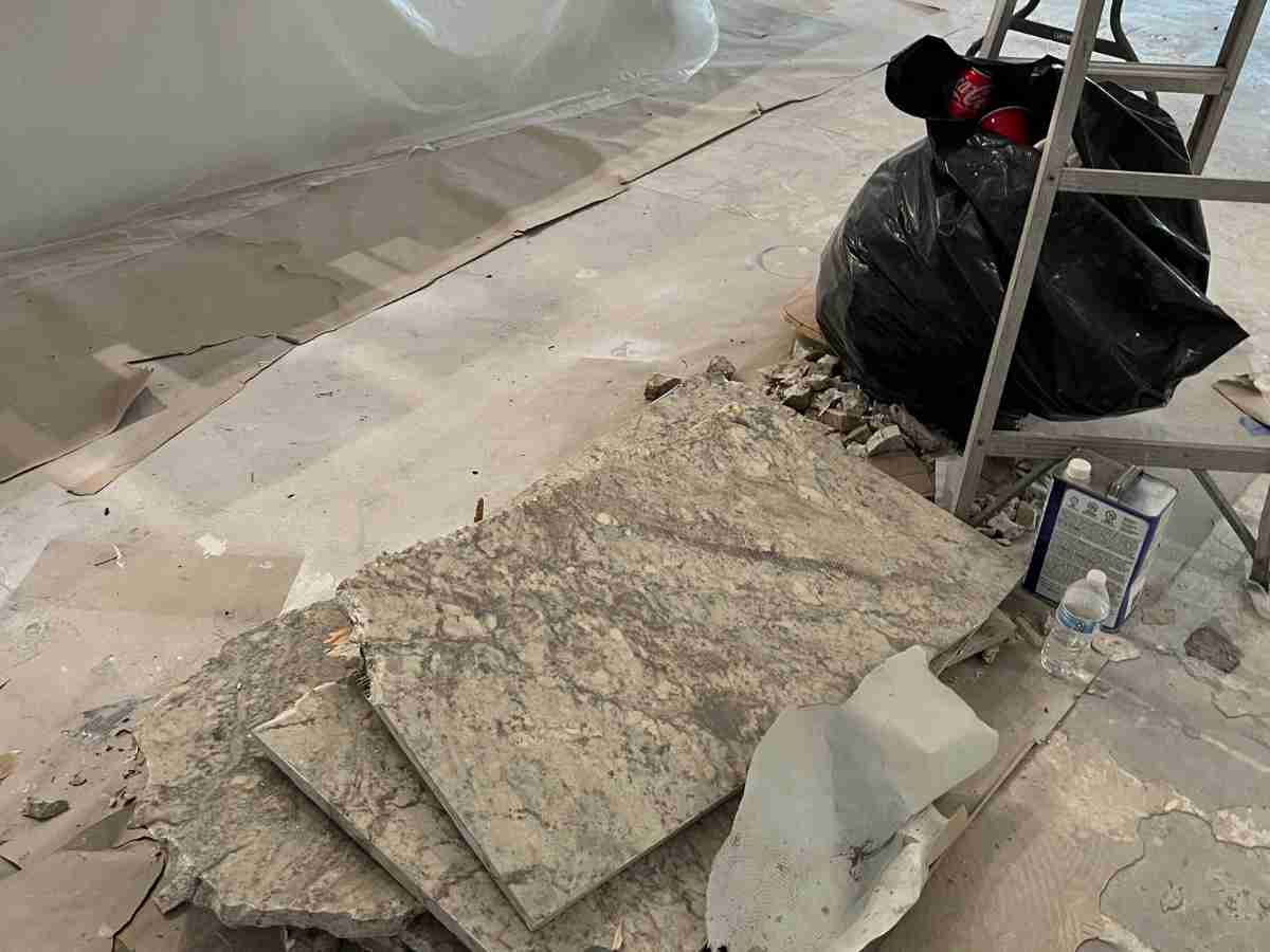 Construction site debris during renovation with damaged granite slabs and materials, showing how delaying repairs can raise mold removal costs.