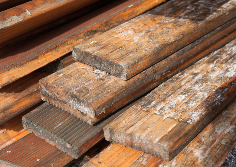 Stacked wooden planks with visible mold growth and discoloration.