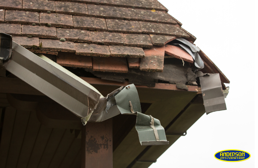 Close-up of severe roof and gutter damage from a storm, used by Anderson Restoration to highlight the need for professional storm damage roof repair."