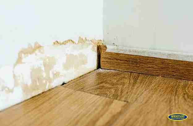 Water-damaged wall and baseboard in a home near College Station, TX, showing peeling paint and moisture damage along the floor — water damage restoration College Station, TX.