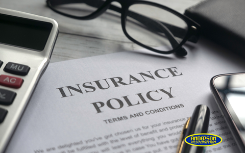 Insurance policy document showing terms and conditions with a calculator and eyeglasses on a desk.