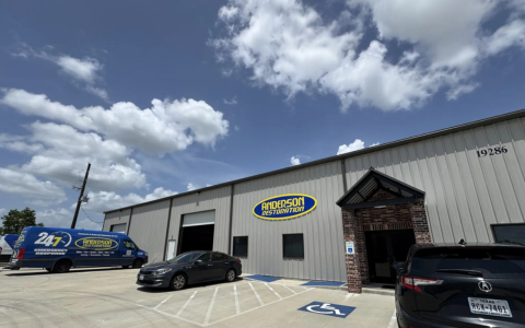 Exterior of Anderson Restoration building with service vehicles parked outside in Houston, Texas.