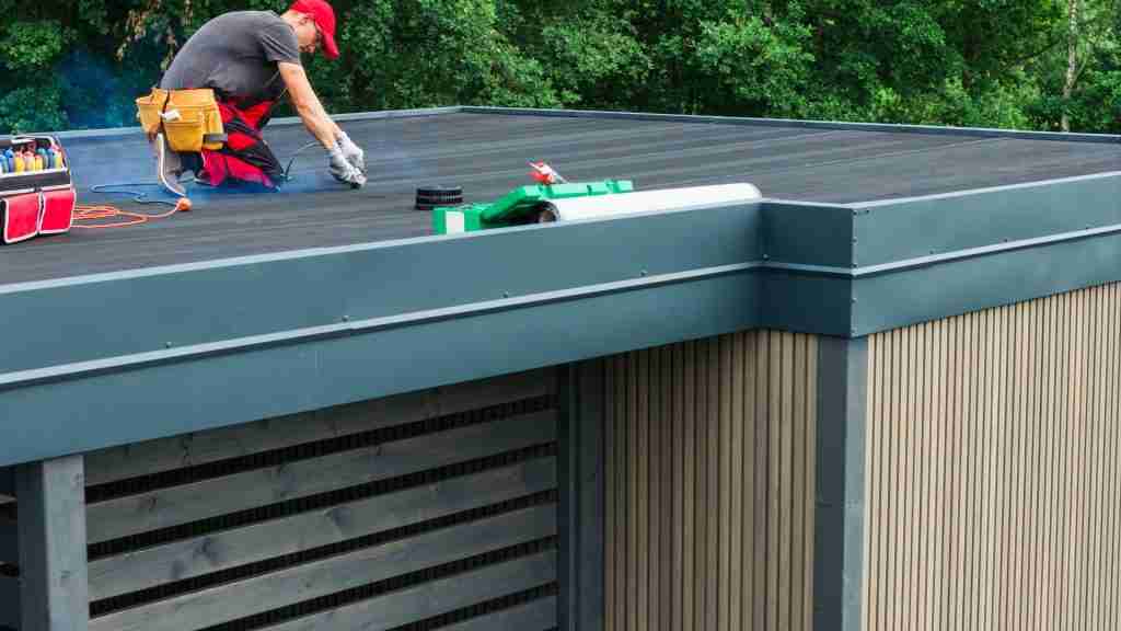 Anderson Restoration technician photographing roof conditions with a tablet during a scheduled maintenance visit on a commercial flat roof