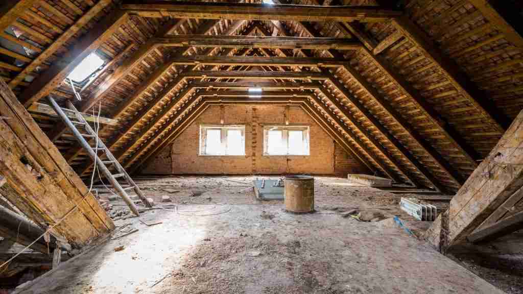 Interior attic view showing condensation on roof decking and rafters in a poorly ventilated Houston home, moisture droplets visible