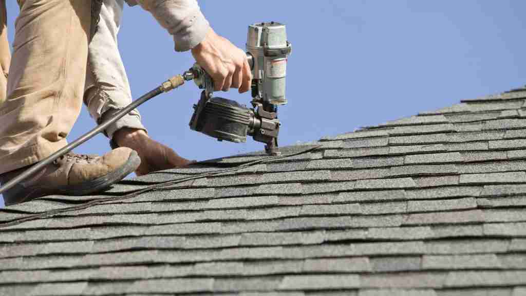 Roofer hand-nailing a Class 4 shingle on a residential roof