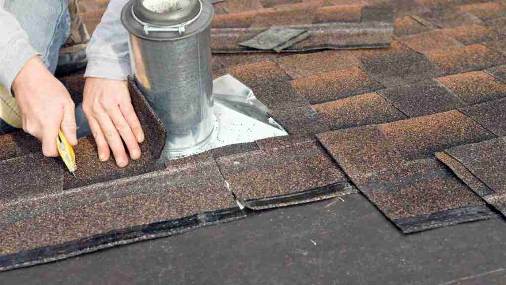 Roofing technician inspecting flashing around a vent pipe on a residential roof, with inspection clipboard in hand