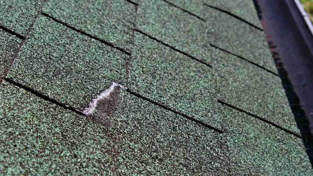 Side-by-side comparison showing a cracked standard shingle next to an intact Class 4 shingle after simulated hail impact testing