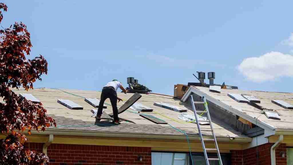 Two-person roofing crew replacing damaged shingles on a single-story home in a North Houston neighborhood