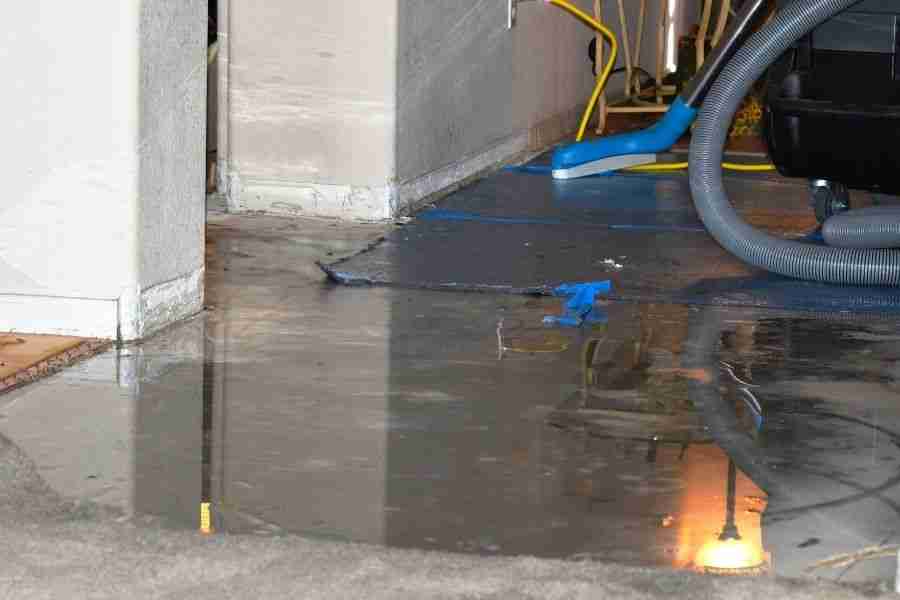 Shop vacuum extracting standing water from a tile floor during water damage cleanup in a Houston home.