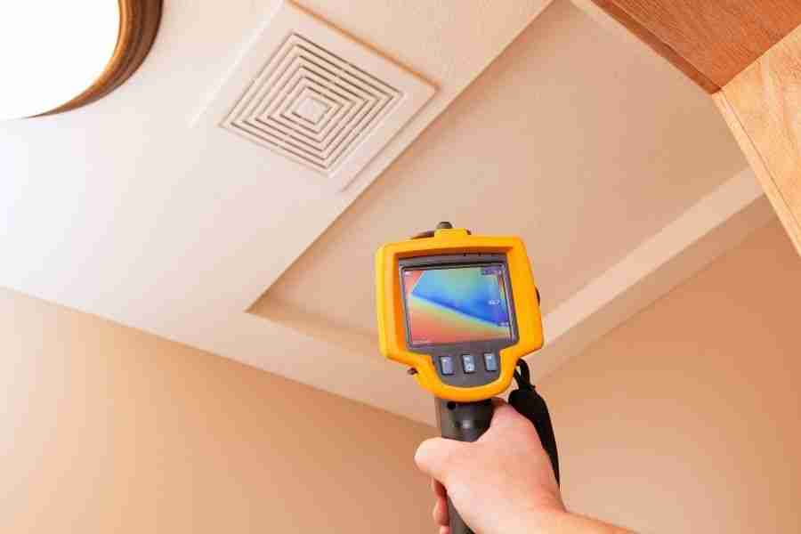 Thermal imaging camera aimed at a bathroom ceiling vent to find hidden moisture during a water extraction visit.