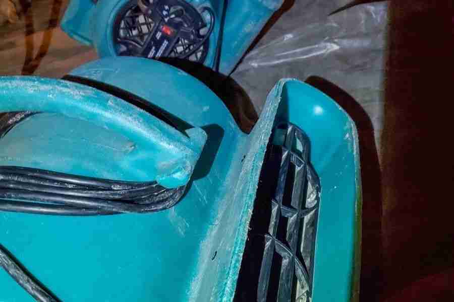 Teal industrial air mover staged on plastic sheeting during crawl space moisture drying work.