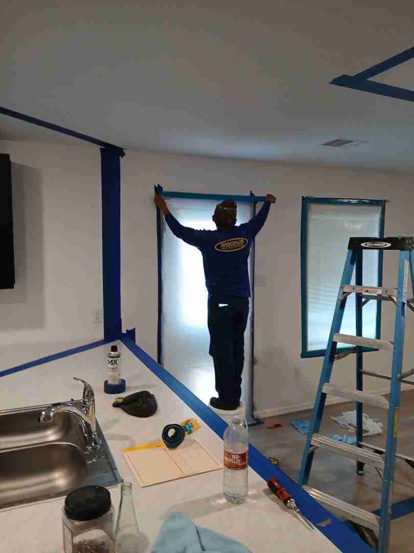 Anderson Restoration technician installing plastic containment doorway in kitchen during Angleton mold project