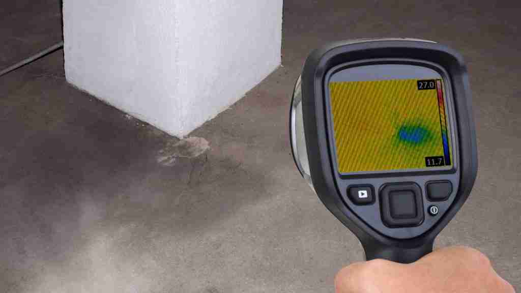 Thermal image scan showing moisture spread beneath kitchen tile flooring extending from dishwasher area toward an island cabinet base