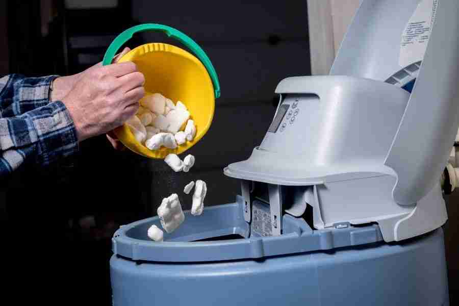 Homeowner lifting the lid on a residential water softener brine tank to check salt levels