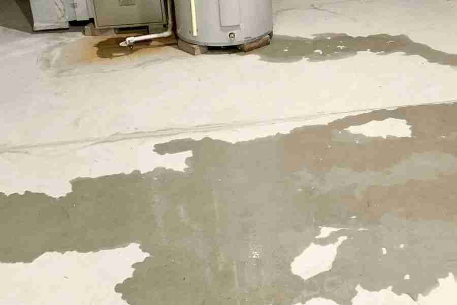 Water damage restoration technician using equipment to dry out a flooded utility room after a water softener failure