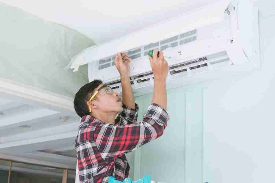 Technician servicing an indoor wall mounted air conditioning unit during routine maintenance in a Houston home