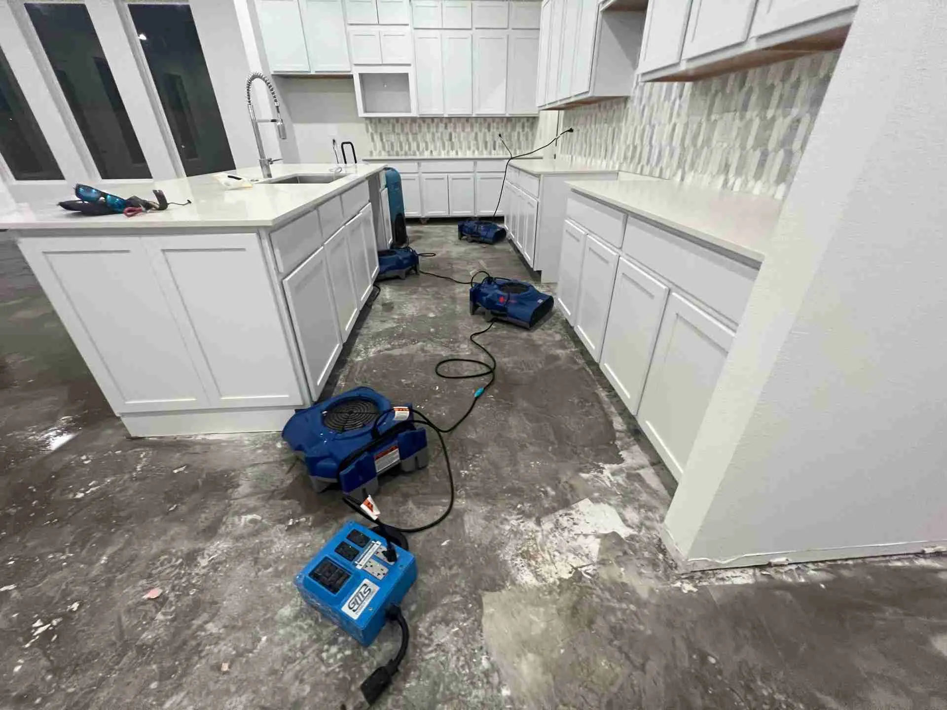 Air movers and a dehumidifier drying a kitchen after water damage in Fulshear TX