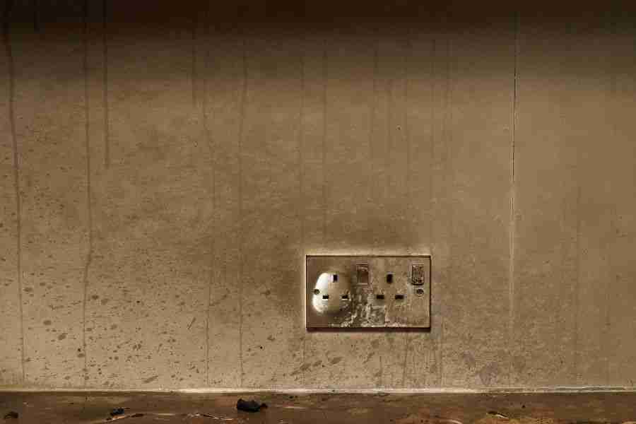 Soot staining and smoke residue coating a wall around an electrical outlet after a house fire