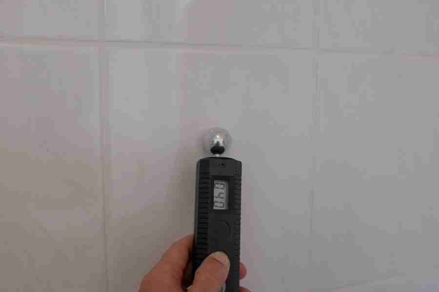 Restoration technician taking a moisture meter reading on wet drywall during a water damage drying job in Houston TX