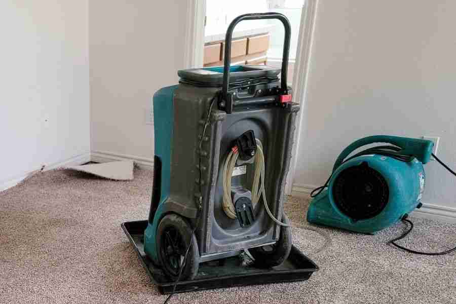 Commercial dehumidifier and air movers running in a flooded living room during structural drying in Houston TX