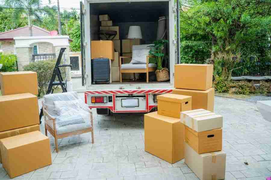 Cardboard moving boxes and wrapped furniture loaded into a truck outside a home during a contents packout